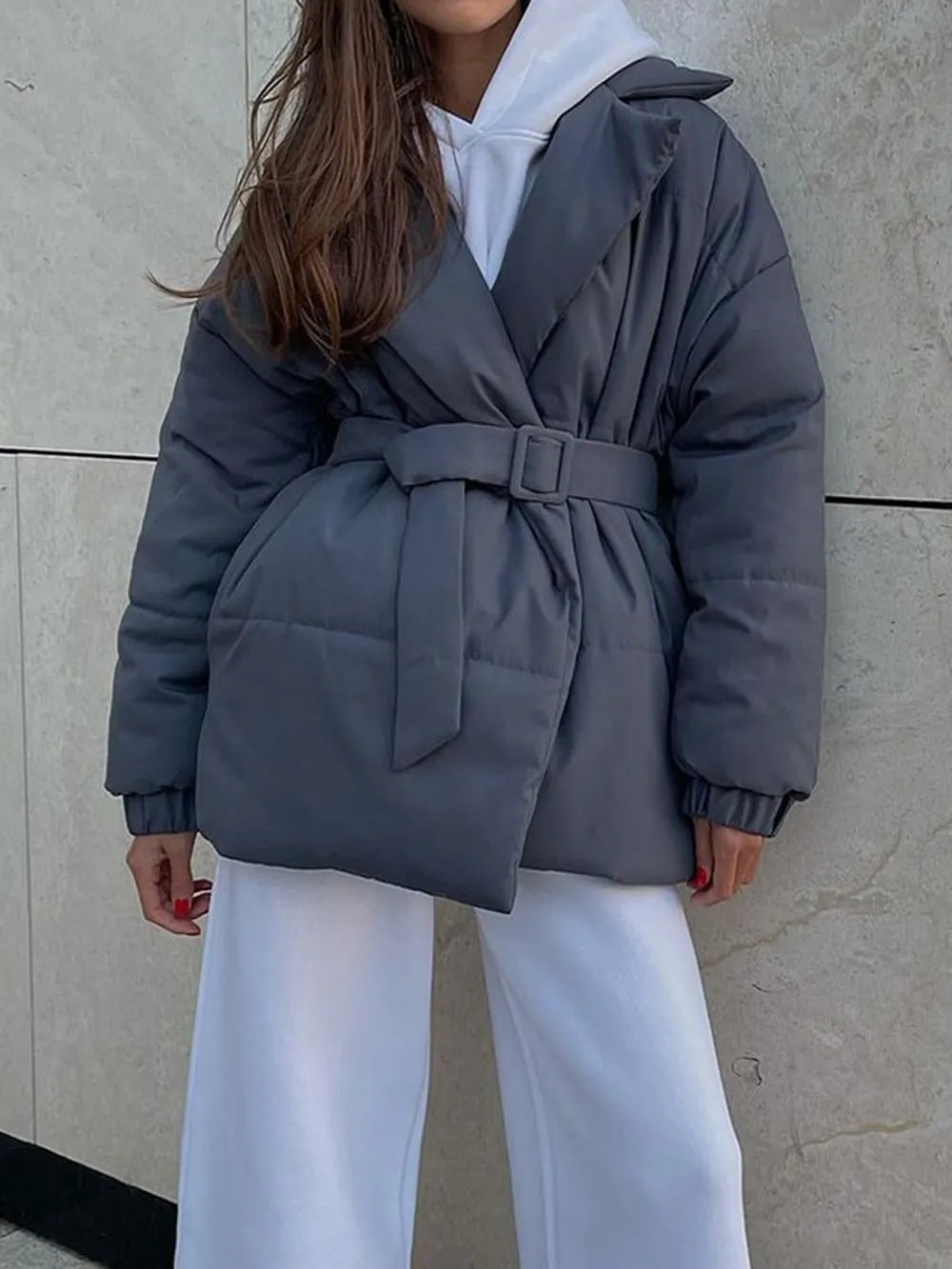 Model wearing a white hoodie, sweatpants and a grey belted puffer jacket from Euriella.